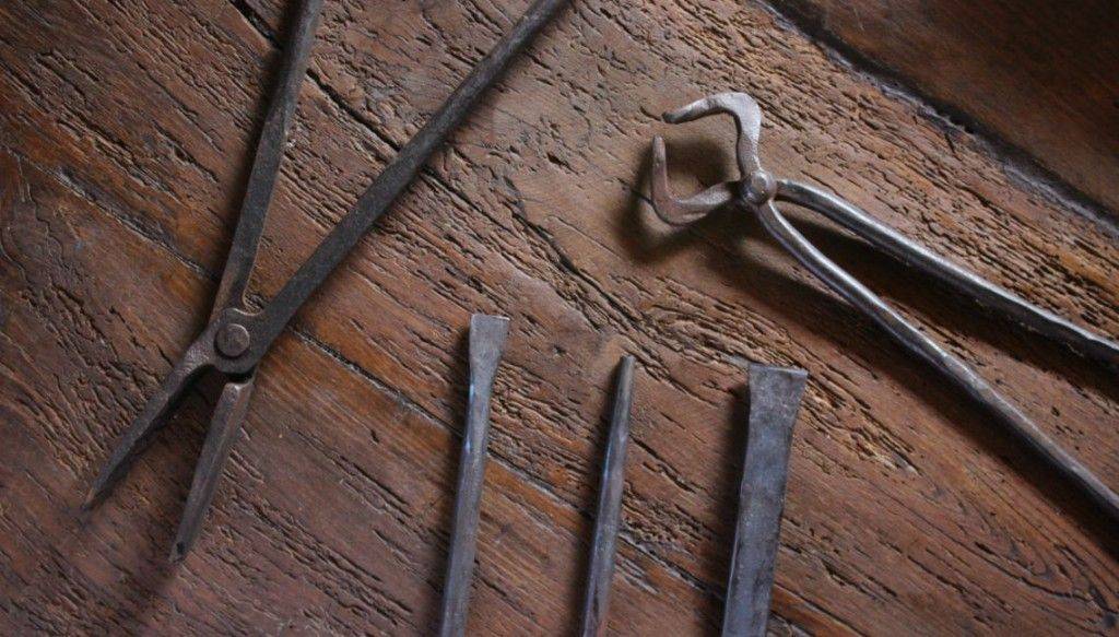 tenazas, punzones y cinceles para trabajar el hierro sobre un fondo de madera antigua