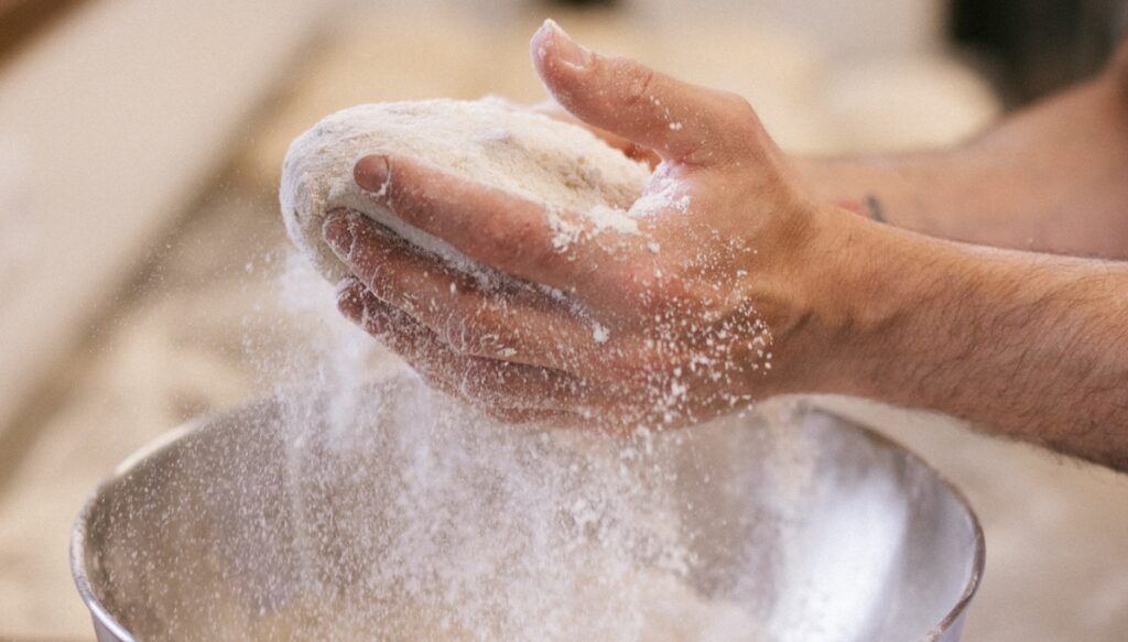 manos amasando pan con harina cayendo para anunciar curso de pan facil